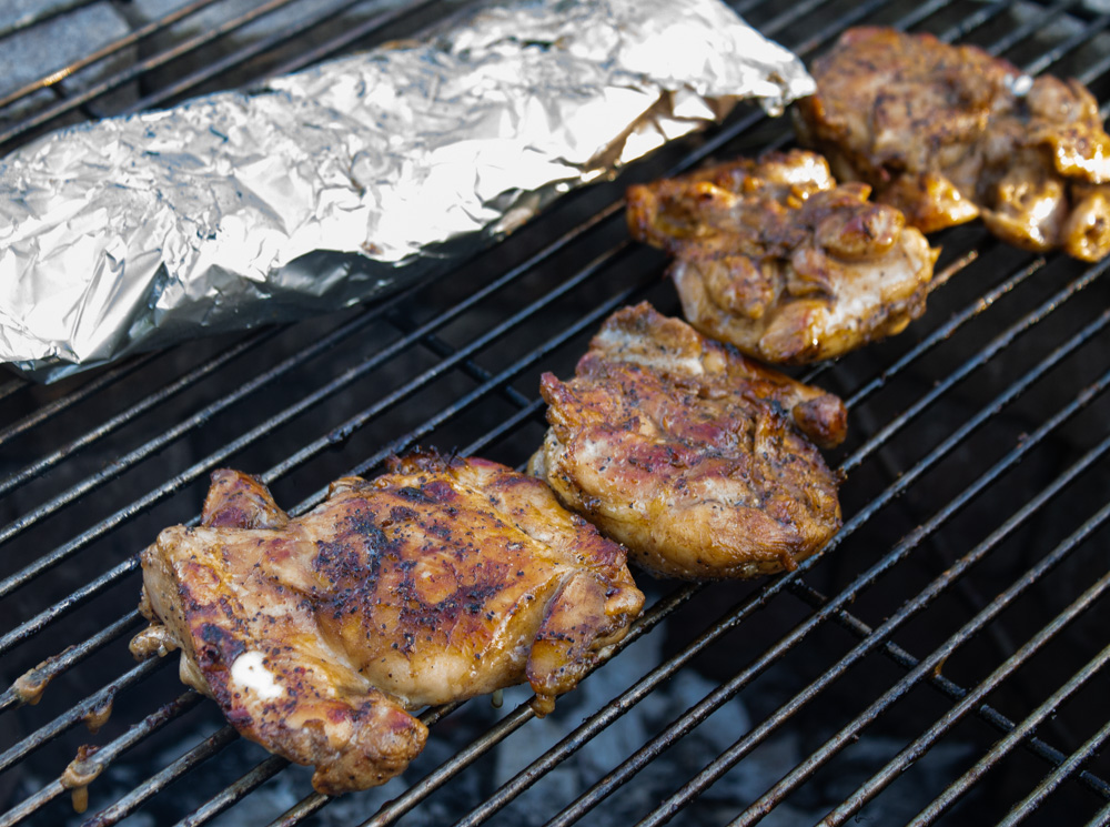 Marinated chicken and foil-wrapped potatoes on grill