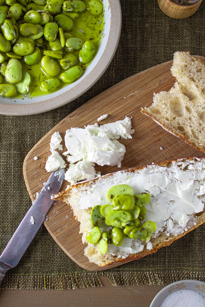 Top view of marinated fava beans on bread with goat cheese