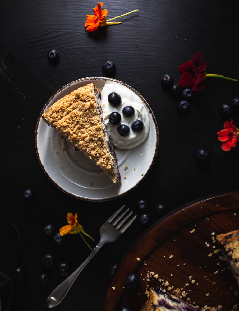 Overhead view of blueberry buckle slice on plate with yogurt