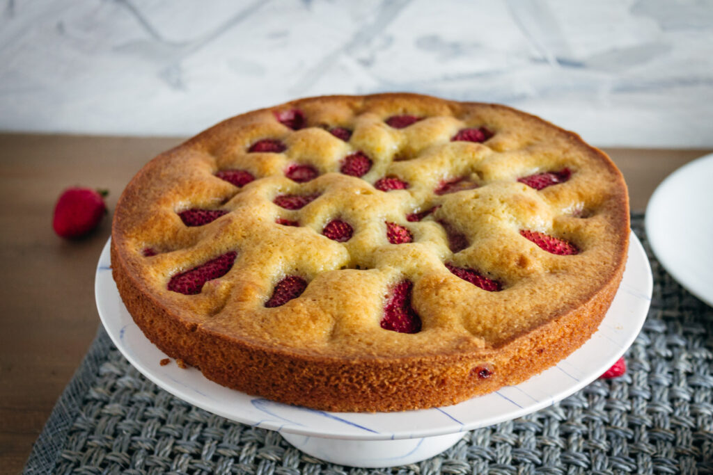 Strawberry olive oil cake on a cake stand.