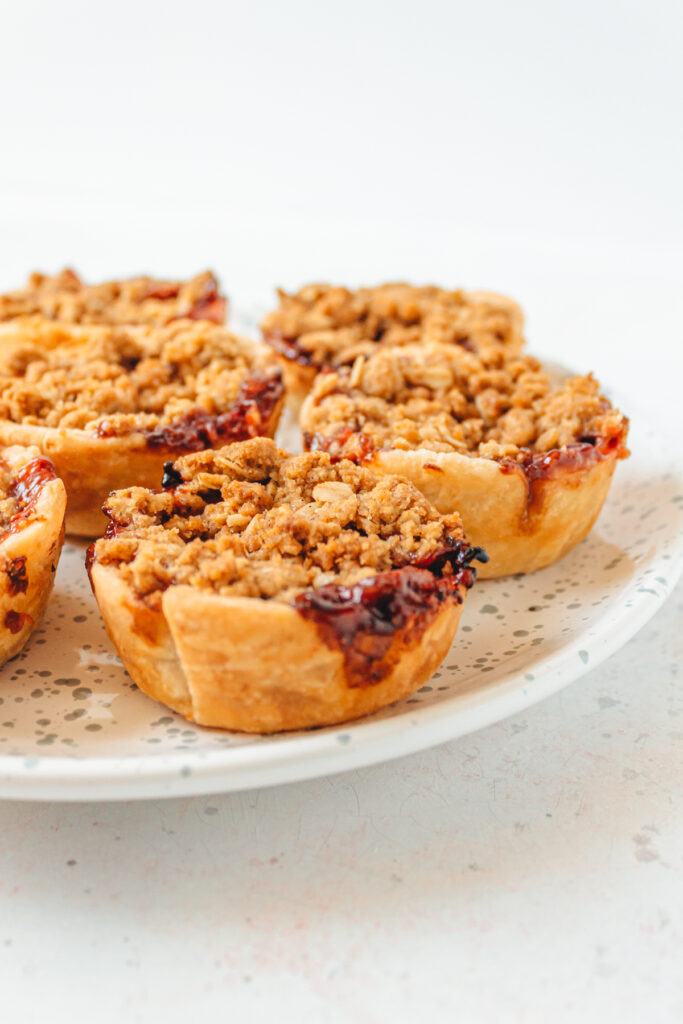 White plate with handheald strawberry rhubarb crisps