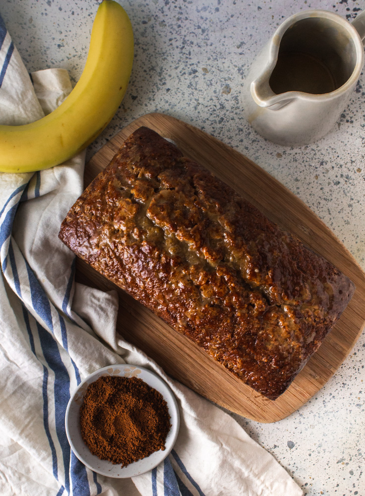 Top view of banana and coffee cake with banana, coffee grounds and white jug