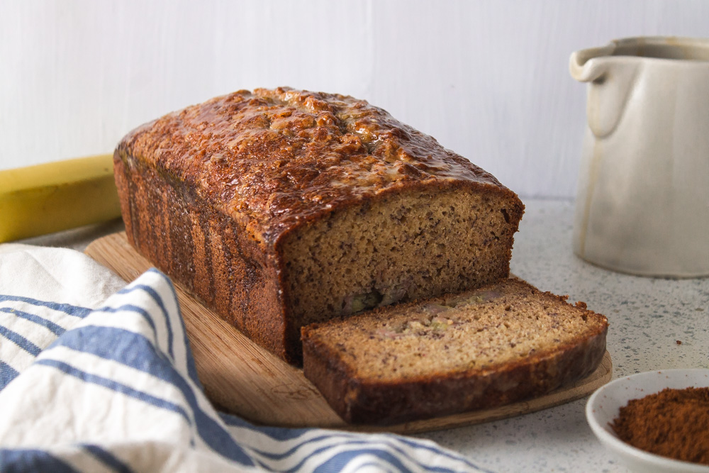 Front view banana and coffee cake with single slice and white jug