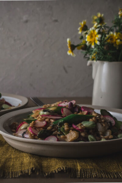 Two plates of farro salad and flowers on a table