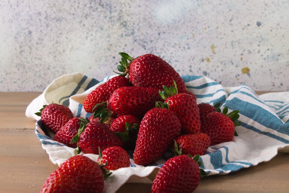 Strawberries on a blue and white cloth.