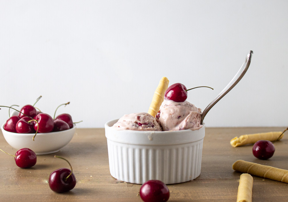 Ice Cream in white ramekin with cherries and cookies