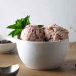 White bowl of cherry mascarpone ice cream with mint sprig