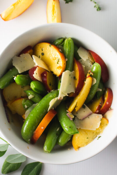 Peach and snap peas salad in white bowl