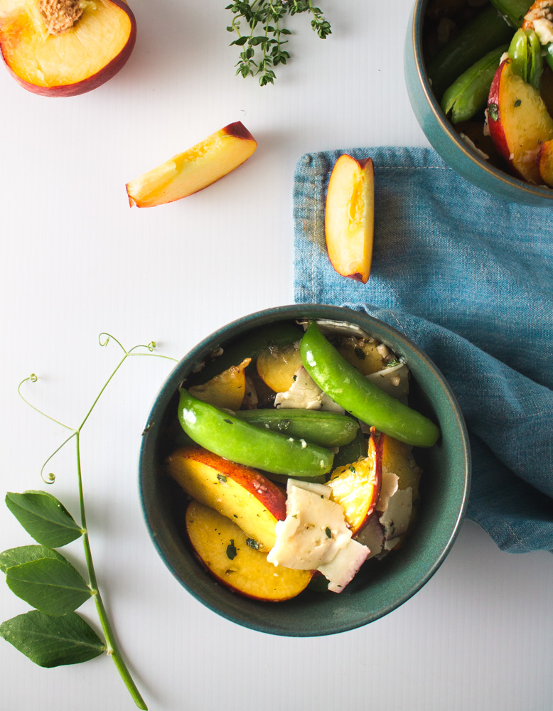 Top view of peach and snap pea salad in teal bowls