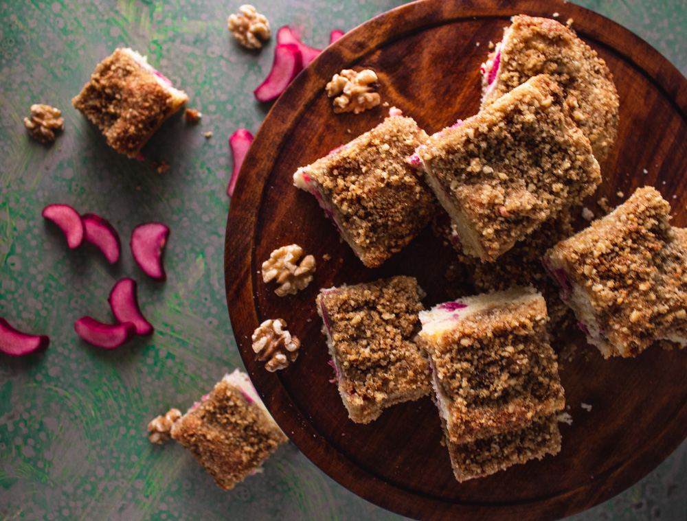 Top view of cut rhubarb cake on green background and wood tray