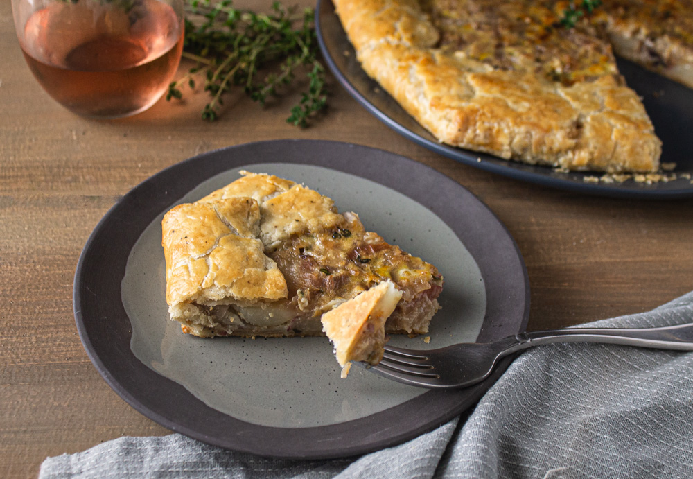 Slice of onion potato tart with fork taking a bite