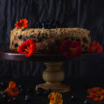 Side view of blueberry buckle on cake stand with nasturiums