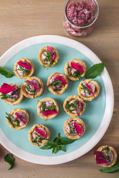 Overhead shot of plum goat cheese tarts on green plate and wood