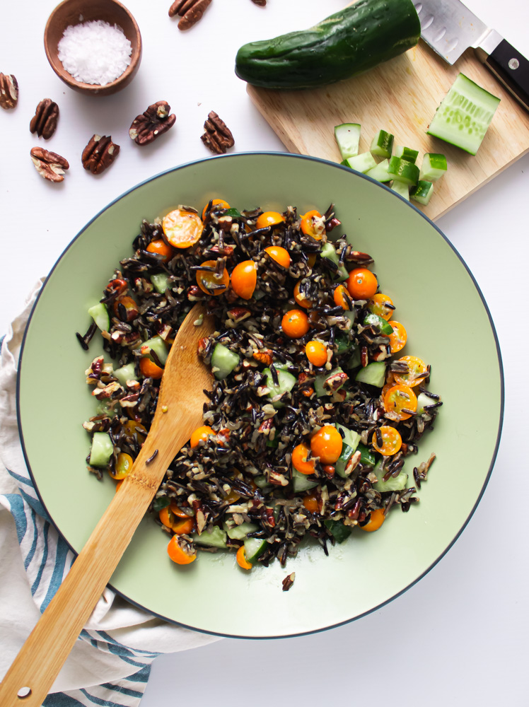 Overhead shot of wild rice salad in green bowl with cucumber