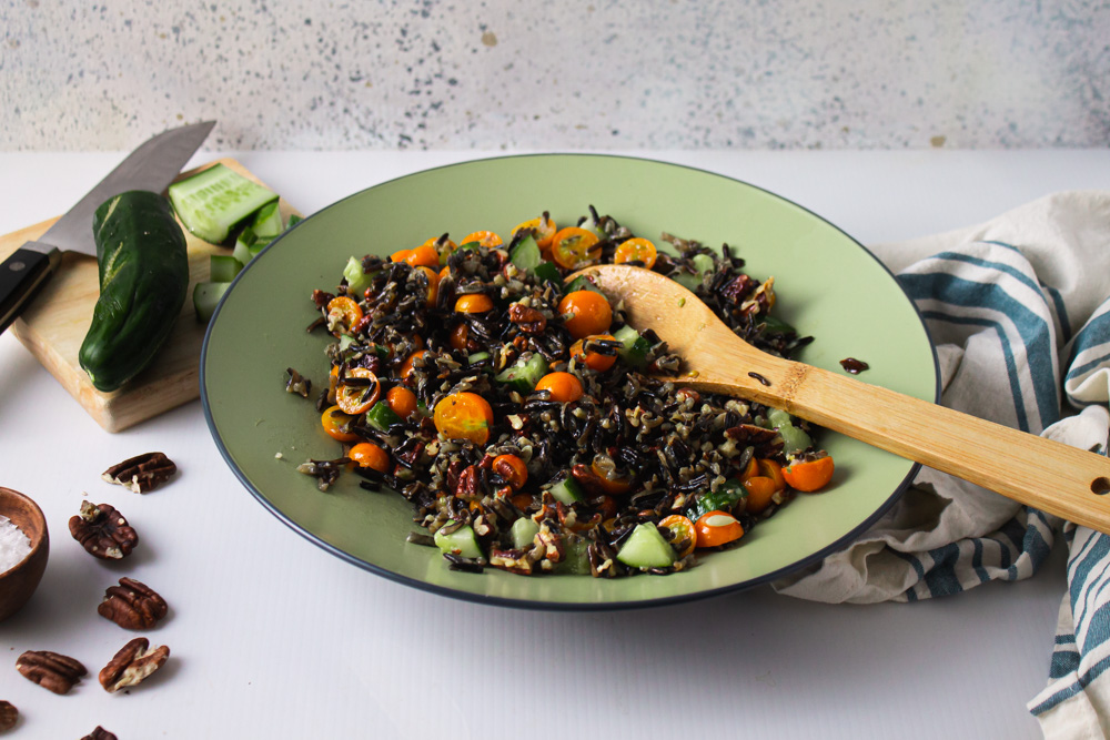 Side angle shot of wild rice salad with cucumber and striped towl