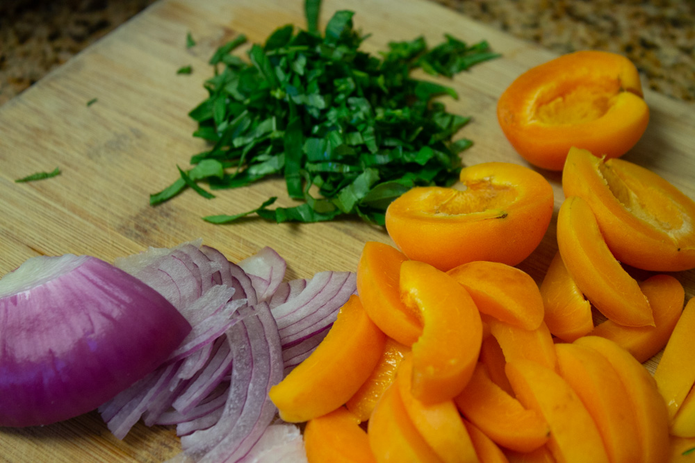 Chiffoned basil, sliced onions and apricots on a cutting board