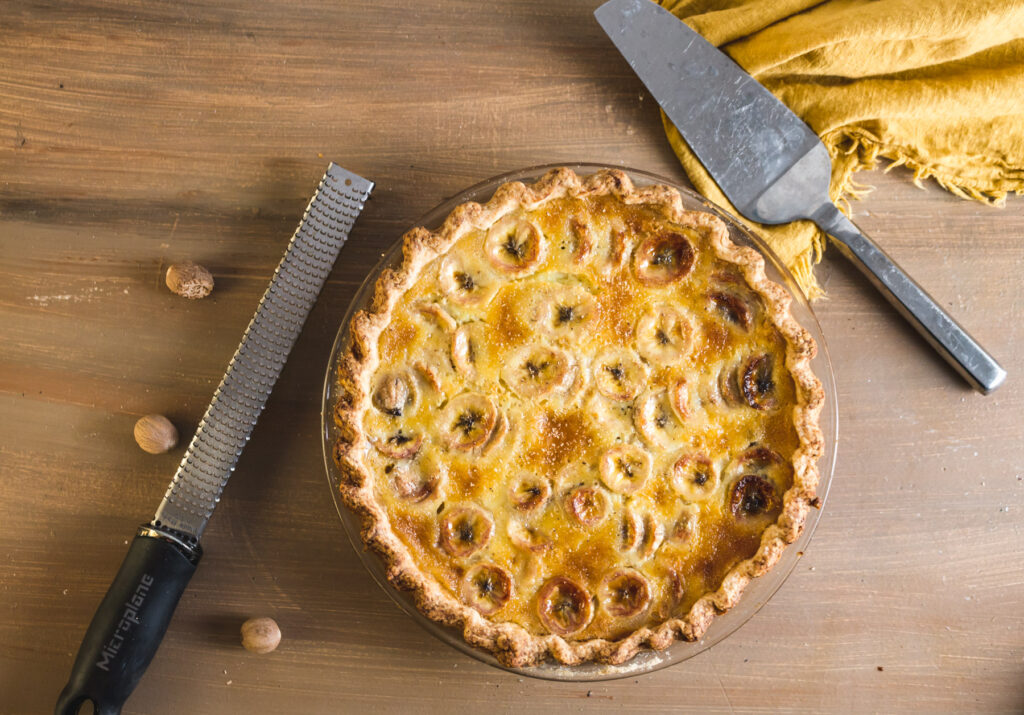 Overhead view of whole baked banana pie on wood table