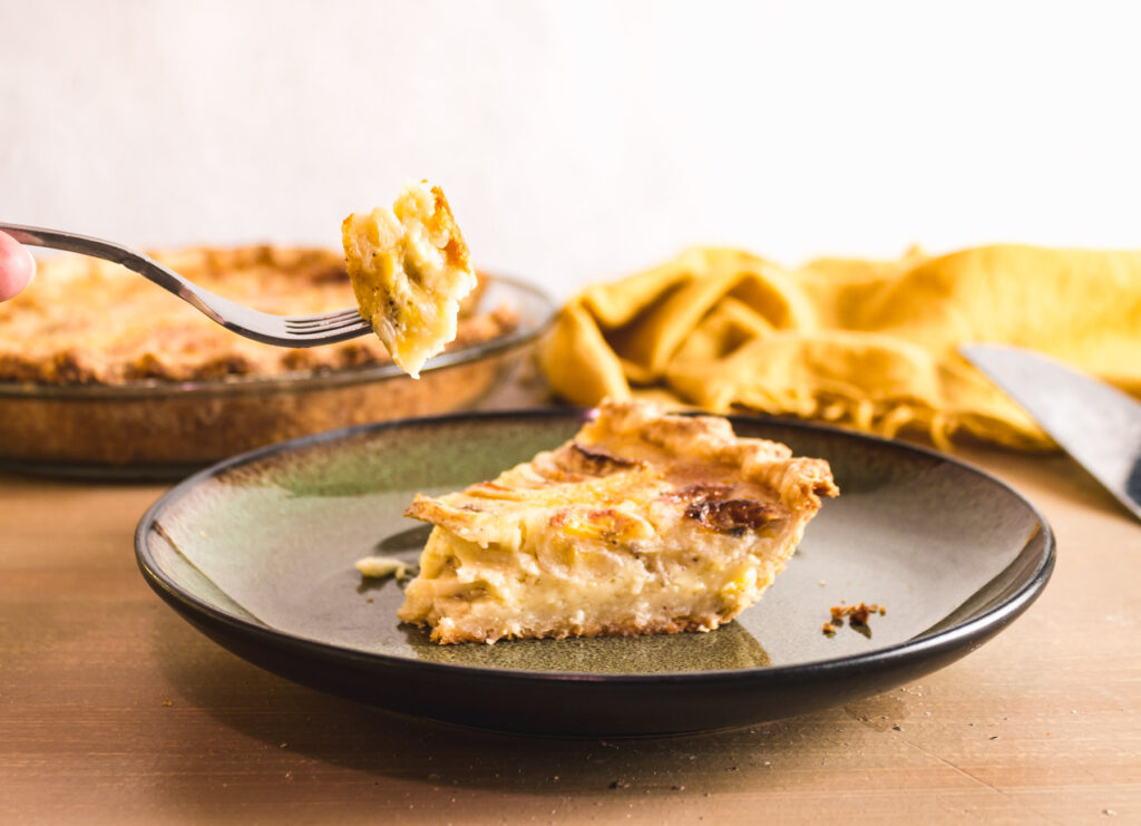 Slice of banana pie on a green plate witha fork taking a bite