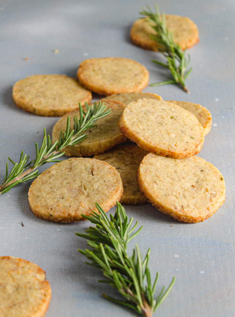 Several scattered blue cheese walnut cookies on a blue background.