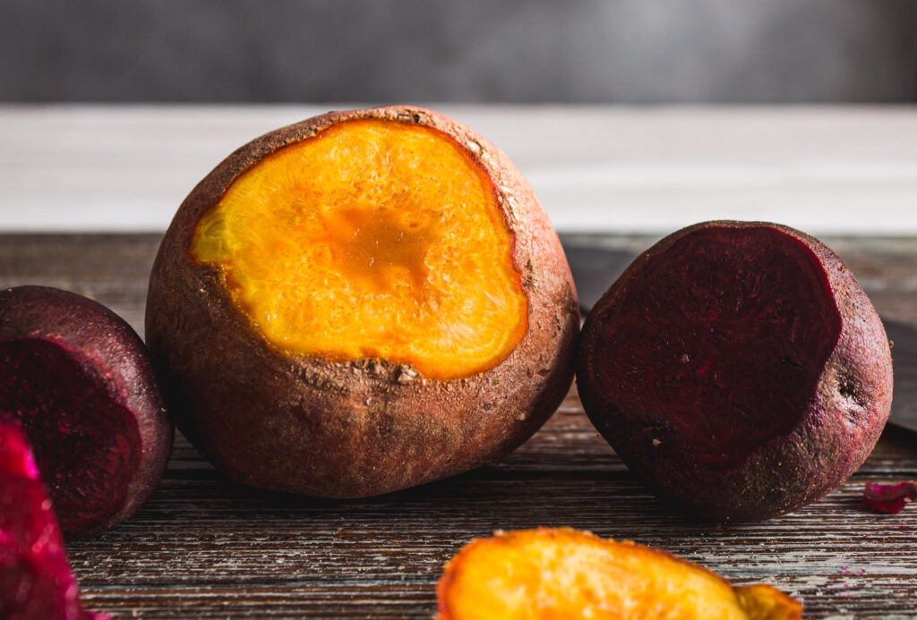 Large golden beet and small red beet, each with their tops cut away showing how much thicker the skin is on a large beet than on a small, fresh beet.