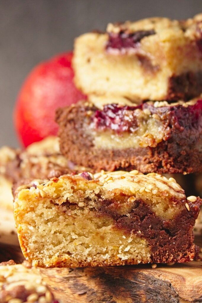 Close up view of stack of three blood orange tahini blondies with a blood orange in the back ground.